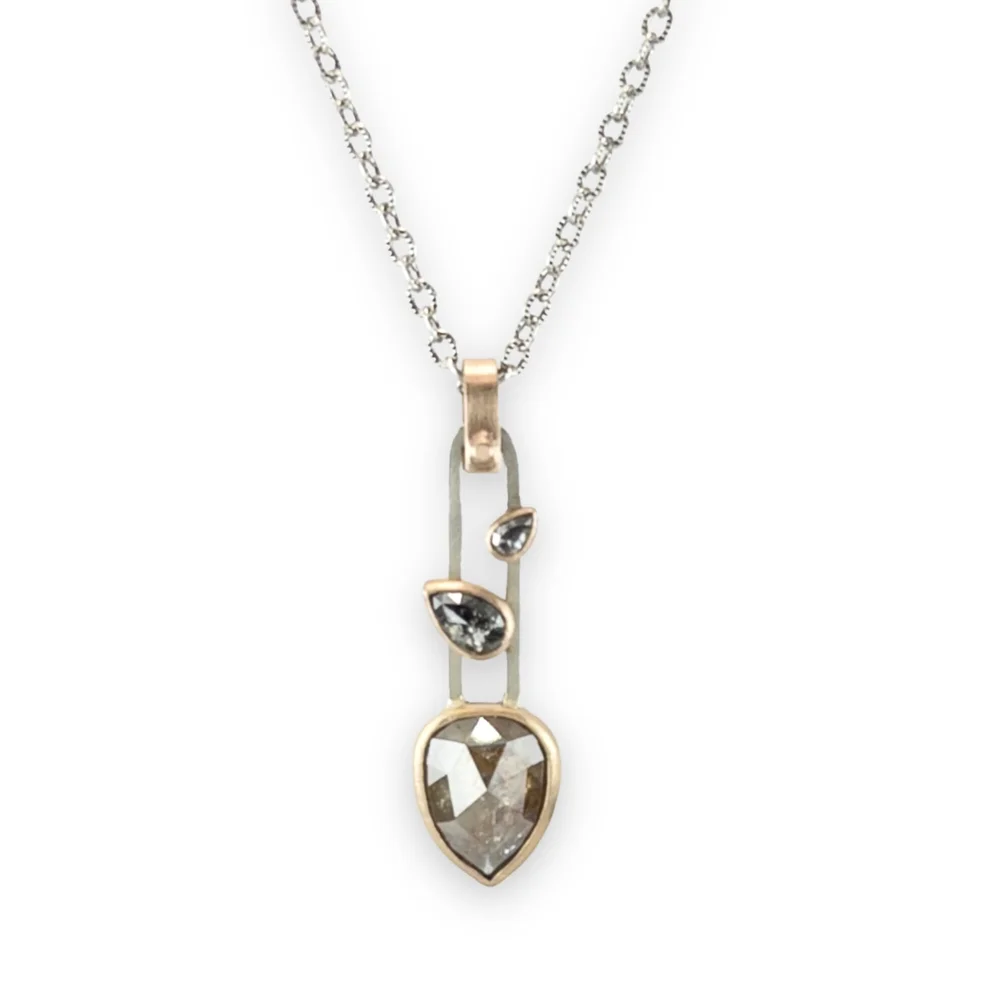 Sterling silver chain necklace with a pendant featuring a large pear-shaped salt and pepper diamond and salt and pepper diamond set in 14 K gold bezels.