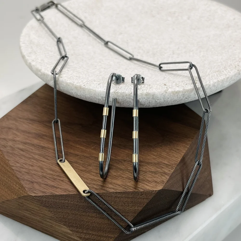 A set of jewelry, including a necklace and earrings, displayed on a two-tone surface with a white circular platform and a wooden base.