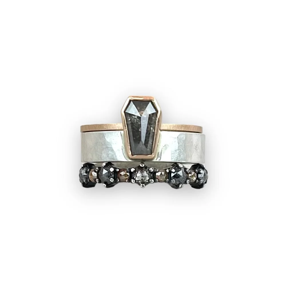 Two rings with black and clear stones, one with a large black gemstone in a gold setting on top of a silver band.
